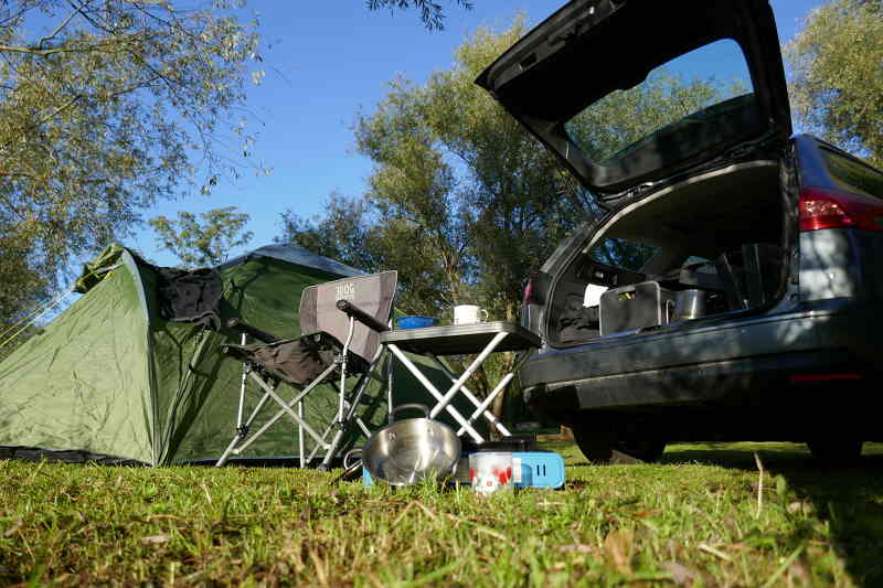 Zelt, Campingsessel und Kombi PKW mit geöffneter Heckklappe, Frühstück am Campingplatz